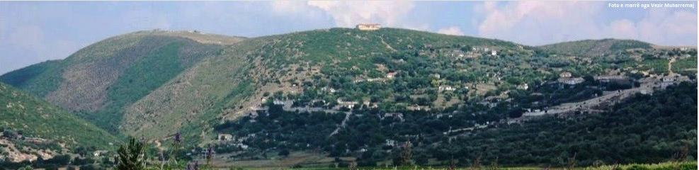 Panorama e Kalivaçit: kodra të gjelbra me shtëpi të shpërndara dhe një ndërtesë në majë